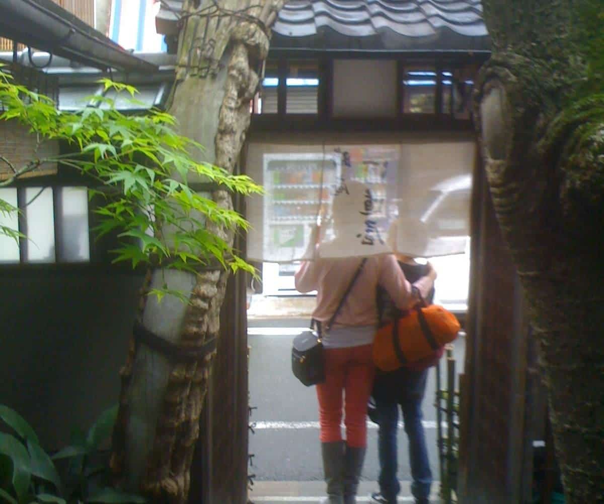 Diners walking through the curtained entrance of a noodle restaurant in Kyoto